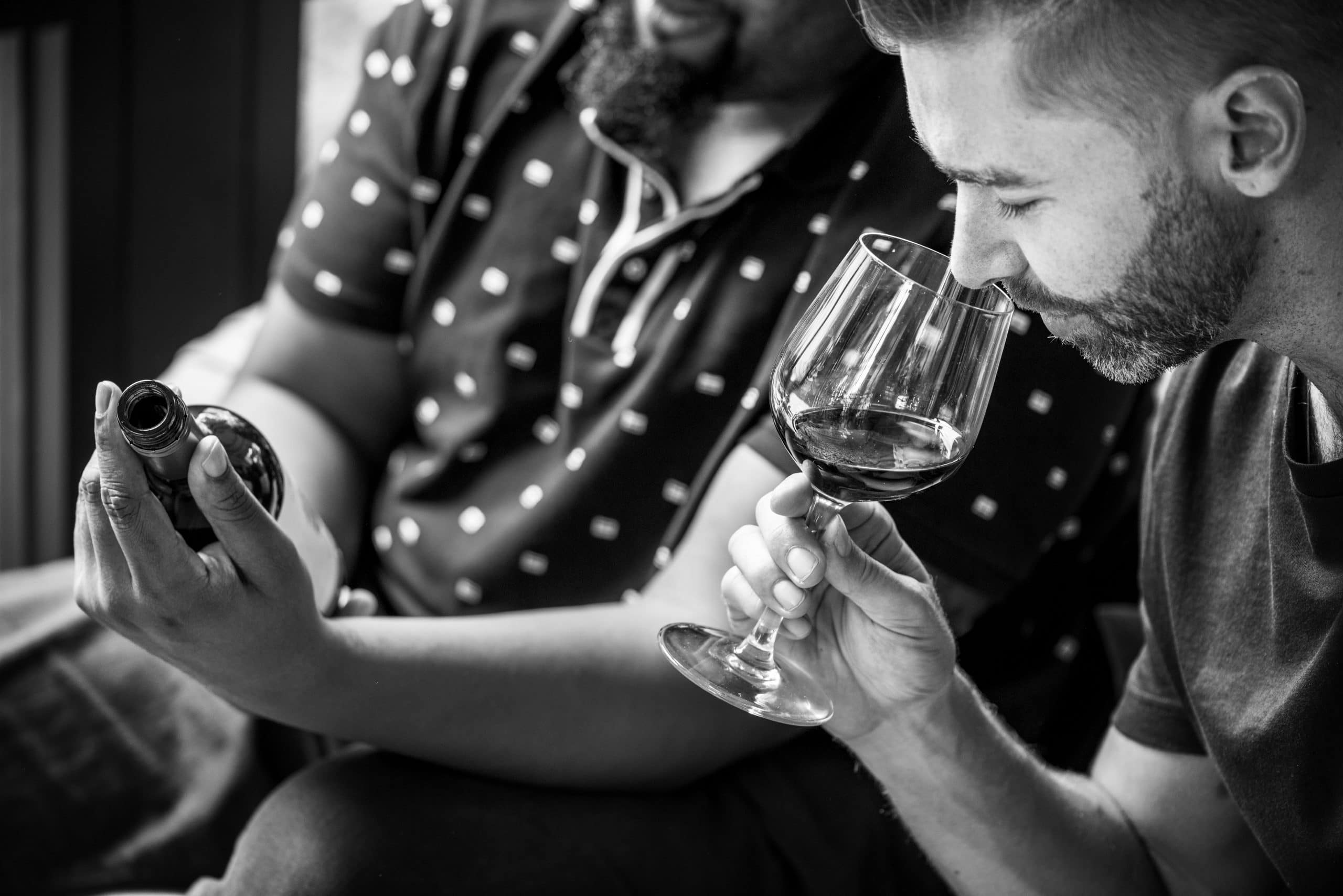 Un homme dégustant du vin avec une autre personne tenant la bouteille